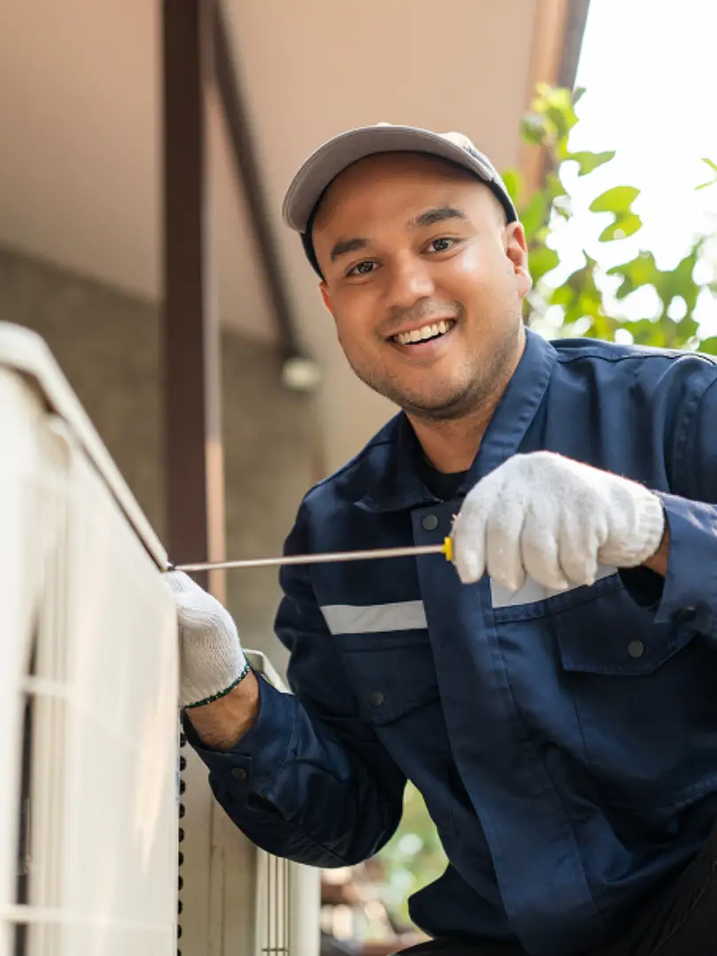 Smiling male service technician in navy uniform and cap measuring or inspecting white building exterior trim