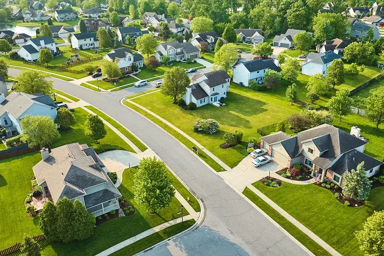 Aerial drone view of a suburban residential neighborhood with multiple single-family homes, tree-lined streets